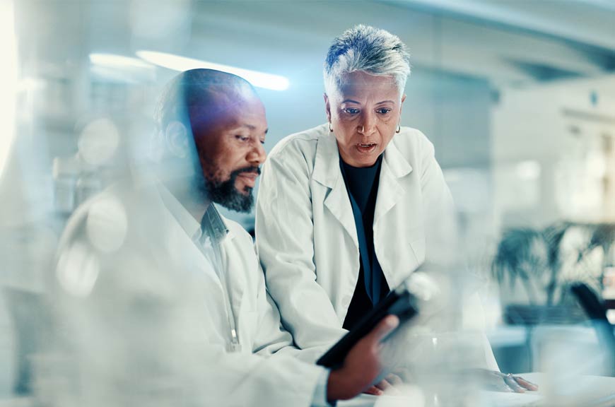 Photo of two doctors chatting about something they're looking at on a clipboard